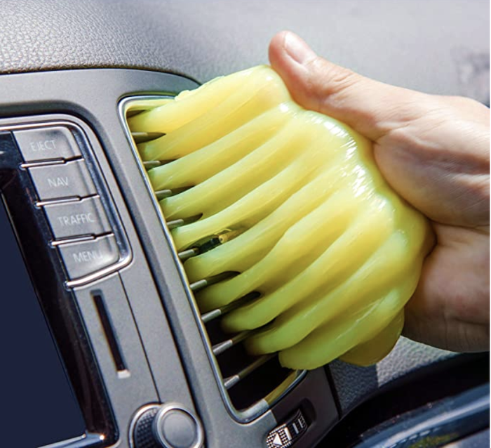 Person using yellow gel to clean an A/C unit in a vehicle
