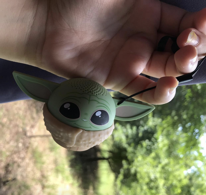 A reviewer holding a Baby Yoda figure.