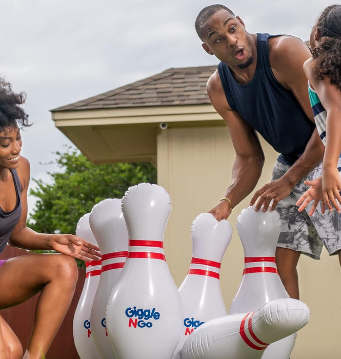 Three people enjoying a game of bowling with oversized pins in their backyard.