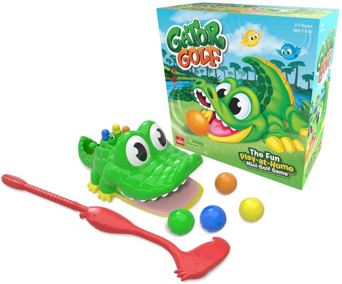 An alligator mouth, golf club, and balls placed next to the game’s packaging.