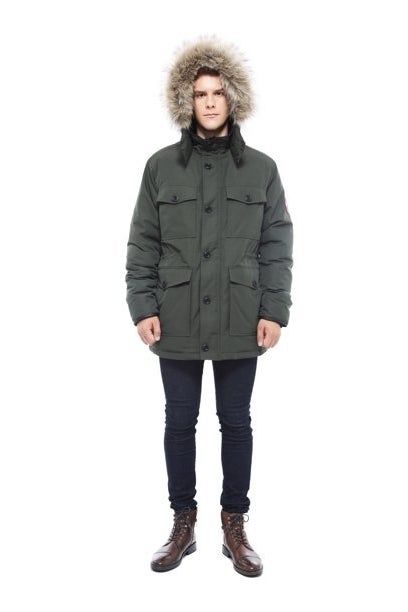 The same model is shown again, wearing the green parka.