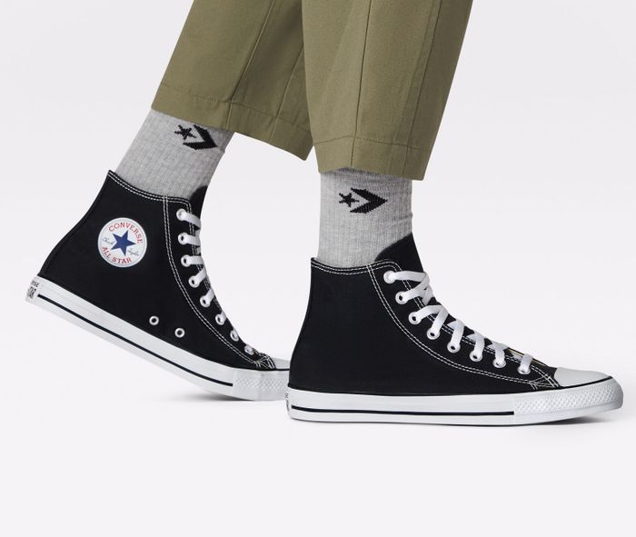A person sporting classic high-top sneakers and gray socks adorned with a star pattern, paired with rolled-up olive pants.
