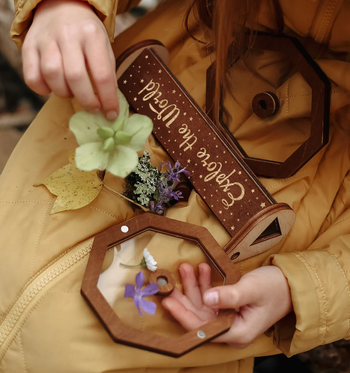 A child carefully placing flowers inside the kaleidoscope's lid to create new designs.