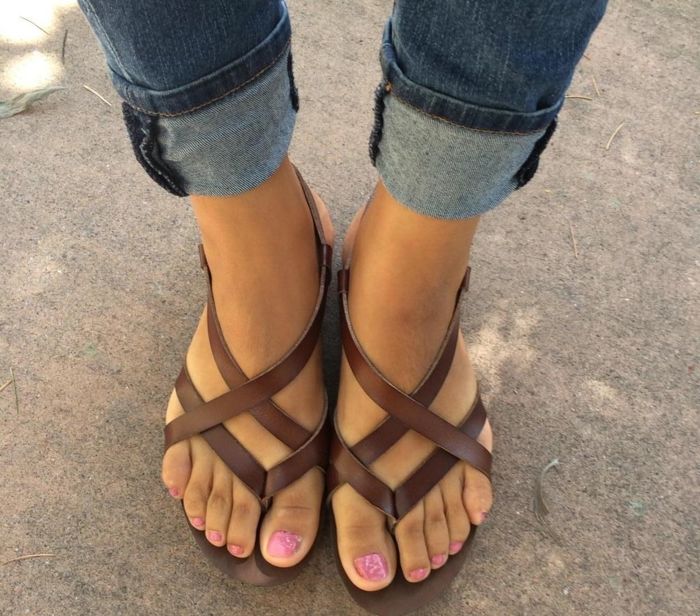 A person wearing strappy sandals and cuffed jeans, showing off their pedicured toes, ideal for a shopping trip.