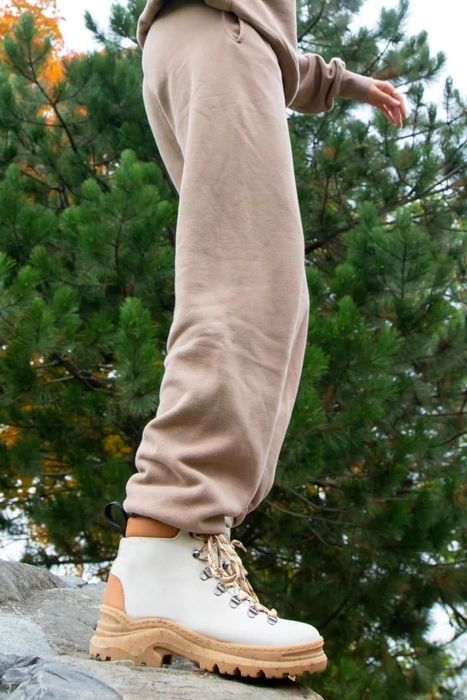 Someone standing on a rock, showcasing beige lace-up boots paired with a casual outfit