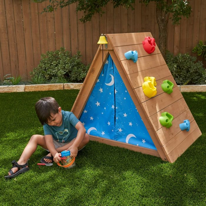 A child relaxes in front of the climbing tent, enjoying the cozy hideaway.