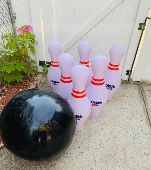 A reviewer shows their large inflatable bowling ball and pins set set up in the yard.