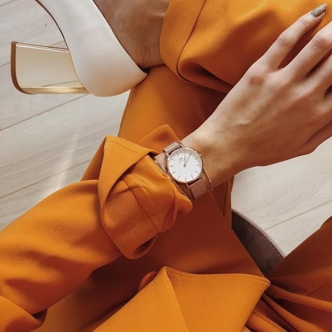A model elegantly wearing a gold watch with a crisp white face, exuding sophistication.