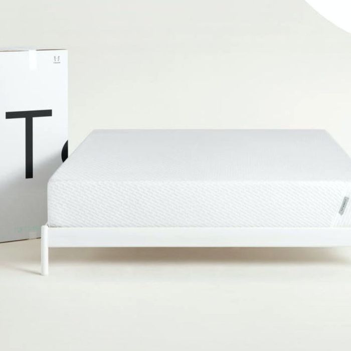 mattress placed on a bare bed frame with a Tuft & Needle box beside it