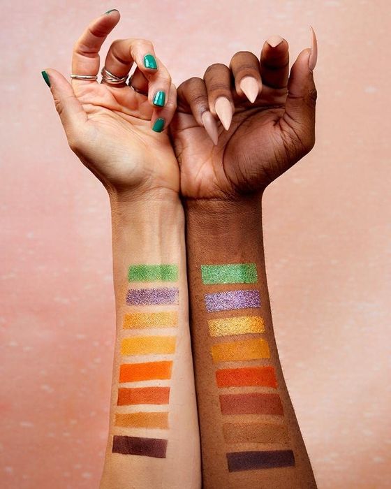 Two different arms showing off the variety of colors in the makeup palette.