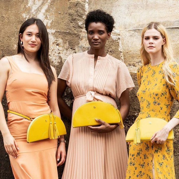 Three models posing with the chic half-moon shaped bag in a vibrant yellow hue.