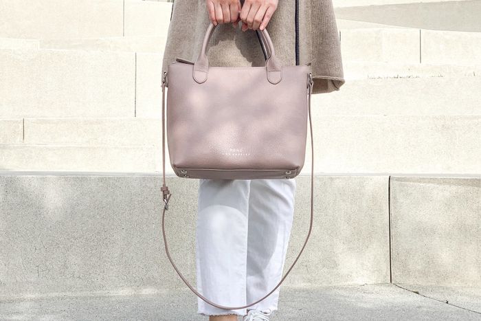 A model elegantly showcasing a blush-colored tote bag, effortlessly blending style and practicality.