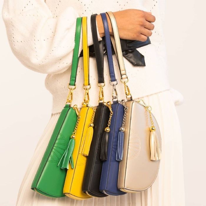 A model elegantly holding five different half-moon shaped bags, showcasing a stunning variety of colors.