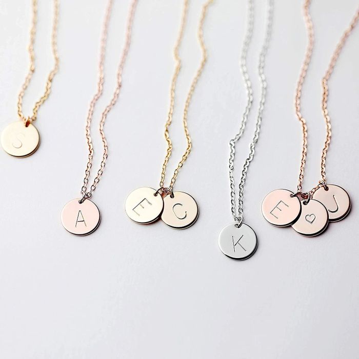 An assortment of delicate necklaces featuring initial disc charms.