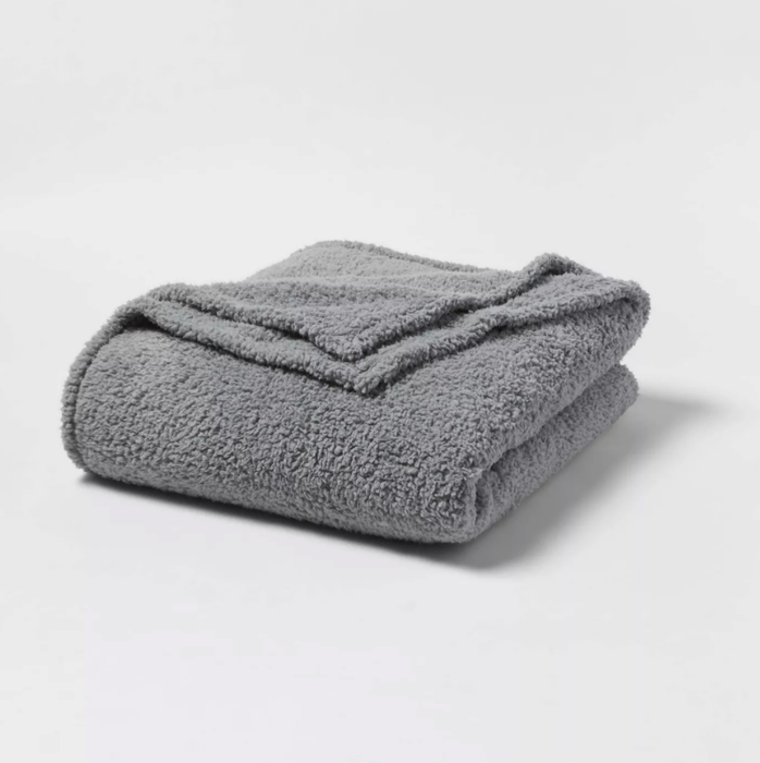 A photo showing a neatly folded gray blanket.