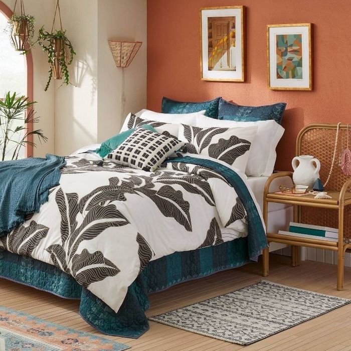 a decorative pillow resting on a vibrant tropical-themed bedspread