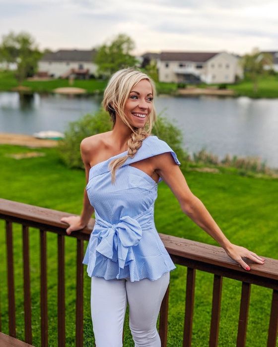 Another reviewer wearing the striped one-shoulder shirt with a ruffled bow tie accent
