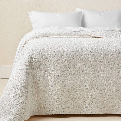 a cozy white dove-patterned quilt elegantly spread over a bed