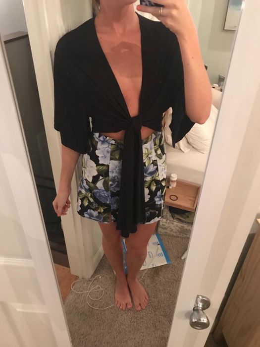 A close-up mirror selfie of the reviewer in the black wdirara short sleeve deep V tie-front shirt.