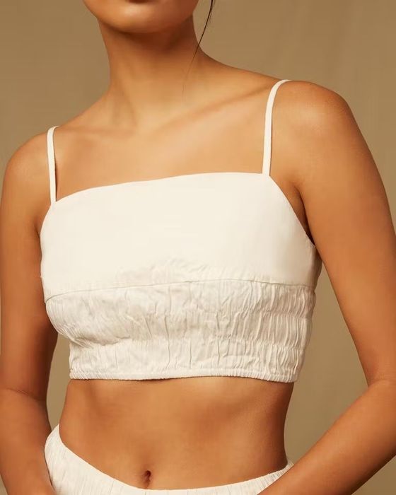 Model wearing a crop smocked top with spaghetti straps.