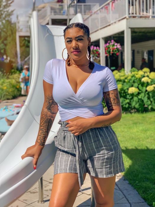 A photo of the reviewer sporting the white Vetior cross wrap crop top alongside plaid shorts.