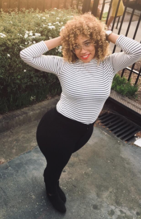 A reviewer styling the white long-sleeve top with slim vertical black stripes