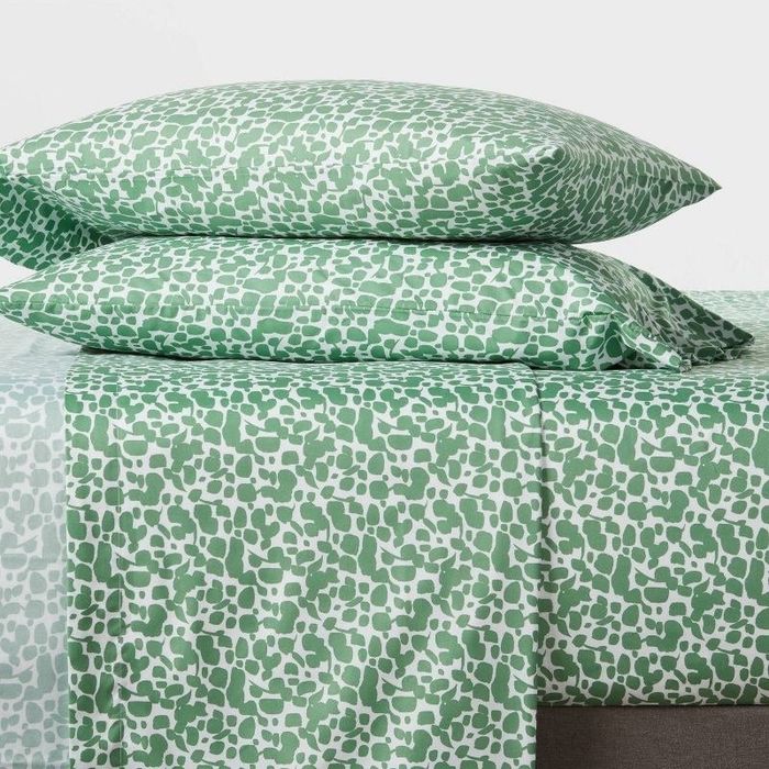 a bed adorned with green and white sheets featuring an elegant pattern