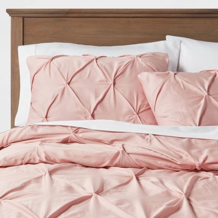 A bed adorned with a pink textured comforter, adding a touch of elegance and charm.
