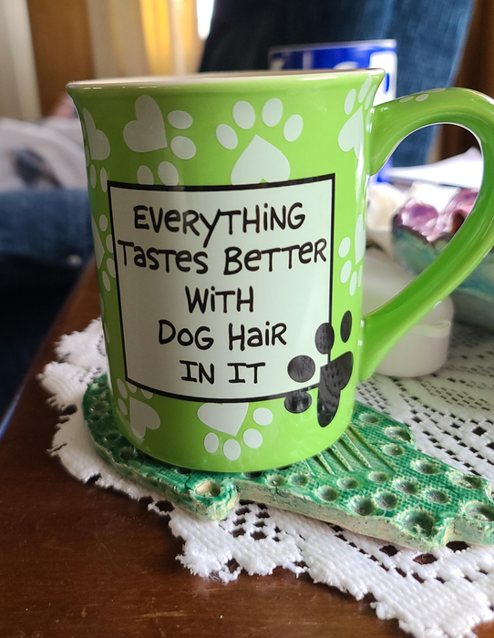 A reviewer's green-colored mug that says