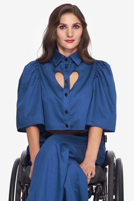 A model wearing a crop top with fluttery sleeves and a heart-shaped cutout