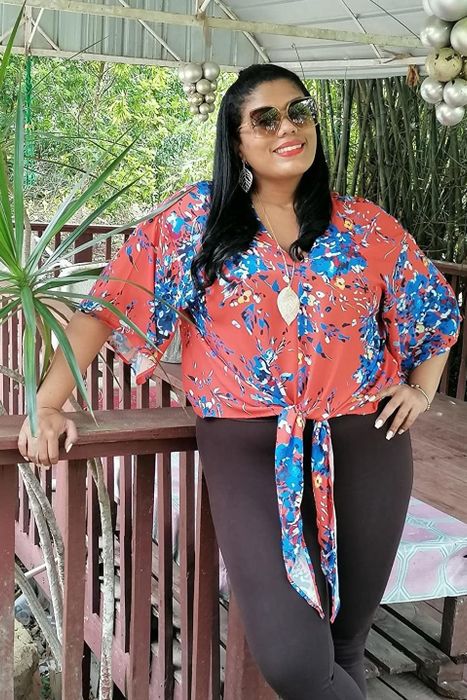 A reviewer wearing the shirt in red with a blue floral pattern