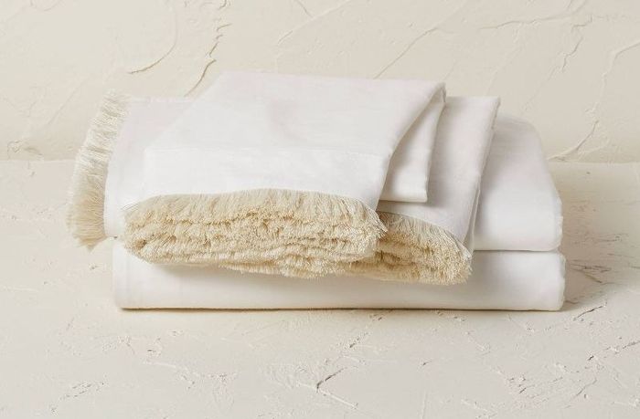 neatly folded white sheets displayed on a textured white backdrop