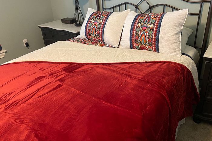 A reviewer's photo of a red blanket neatly spread on a bed.