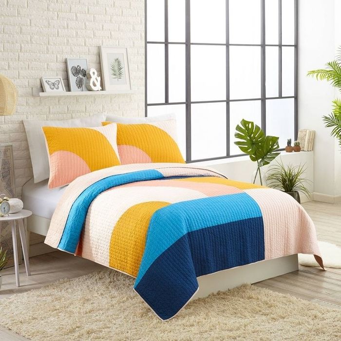 A vibrant comforter that stands out in a bedroom decorated with neutral tones.
