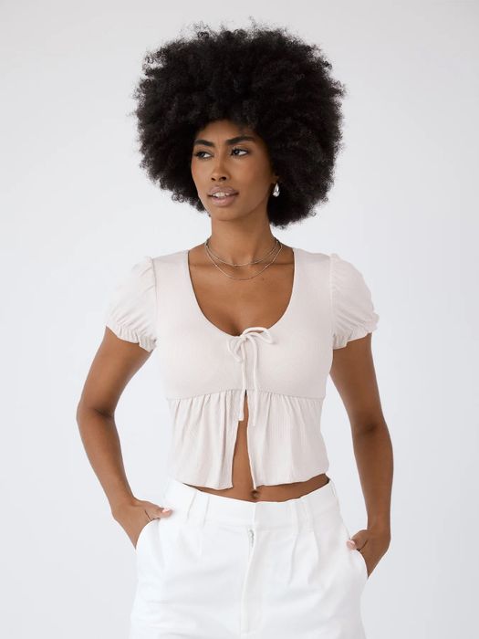 A model wearing a babydoll top with a tie detail in the middle