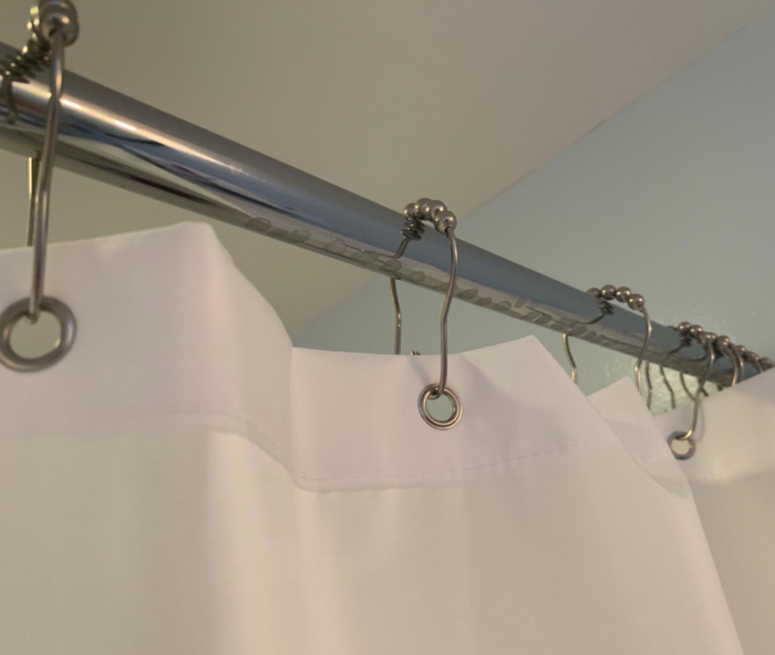 A photo from a reviewer highlighting the reinforced holes used to hang the shower liner.