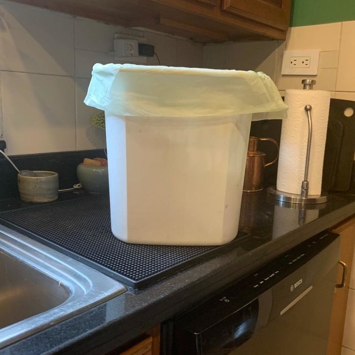 A photo from a reviewer showing a small trash can on a countertop with a compostable liner inside.