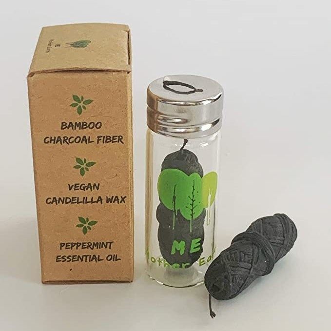 The cardboard packaging and glass tube filled with floss, accompanied by a refill bundle of floss.