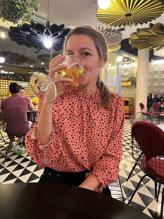 A woman wearing a polka dot blouse enjoys a drink at a restaurant.