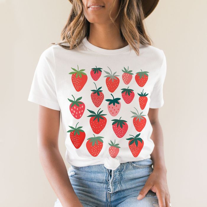 A model sports a white T-shirt with a strawberry print, matched with a pair of jeans.