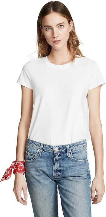 A model sports a plain white tee and blue jeans, accessorized with a red bracelet on their wrist.