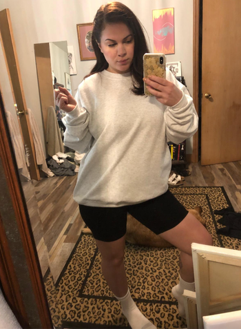 A reviewer wears a gray crewneck sweatshirt with bike shorts.