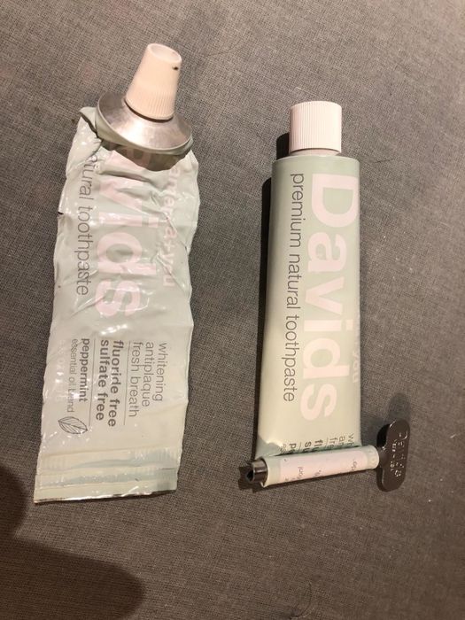A reviewer’s photo showing a wrinkled toothpaste tube and a full one, with a key at the end to help squeeze out the remaining toothpaste.