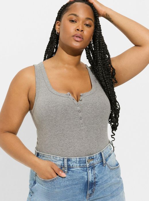 Model wearing a gray button-front casual tank top and jeans, with hand resting on head.