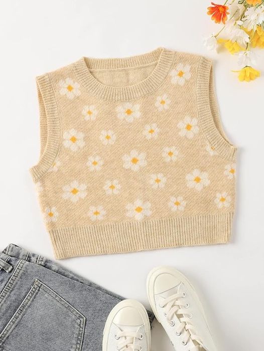A knit vest with a floral pattern, paired with gray jeans and white sneakers, styled in a flat lay for a shopping article.