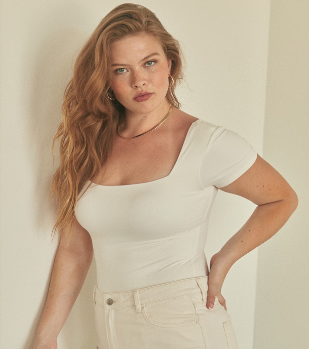 A model showcases a white bodysuit paired with white jeans.