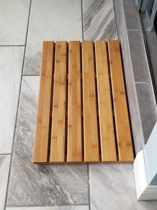 A reviewer photo showing the slatted bamboo mat laid out on the bathroom floor.