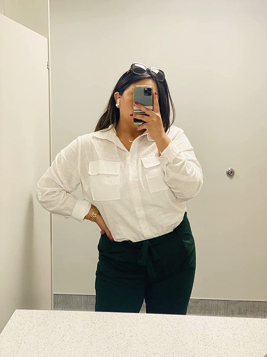 A reviewer styled in a white top, neatly tucked in and buttoned up.