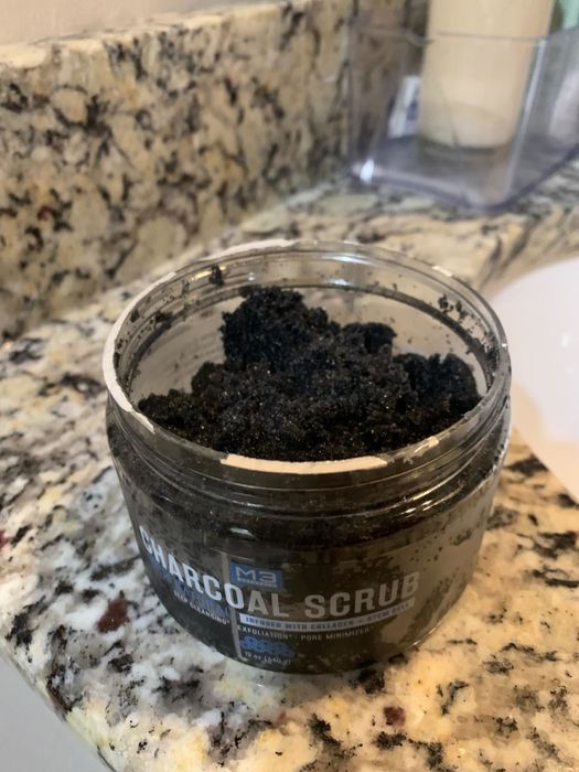 A reviewer's photo of an open tub revealing the black charcoal scrub inside.