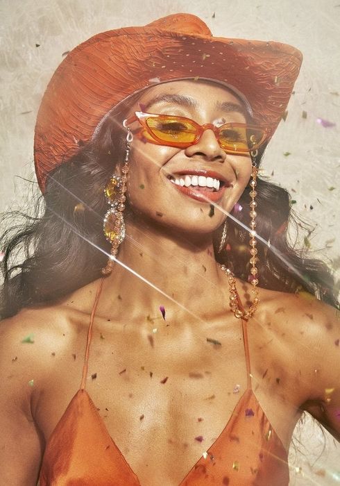 The model sporting an orange discoball chain attached to a pair of sunglasses.